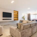 Sala de estar moderna com painel para TV e design minimalista no projeto Leonardo Souza